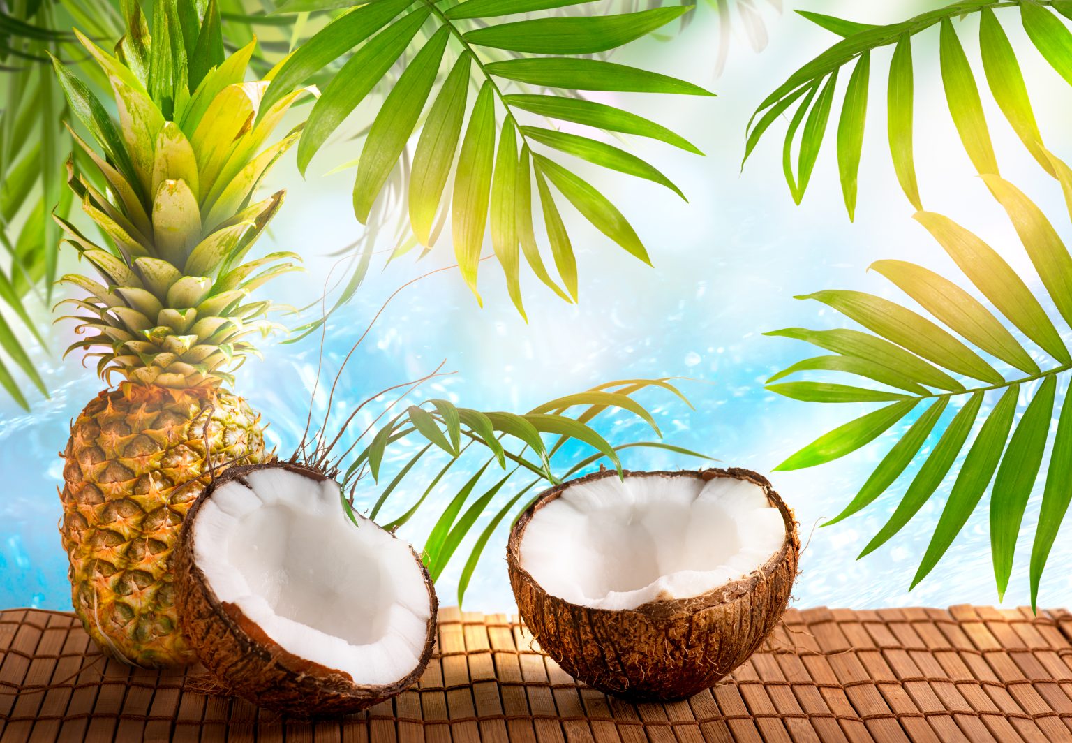 Pineapple and coconut on crystal blue pure sea or ocean background with palm tree leaves and sun rays, tropical Caribbean or Hawaiian paradise landscape, summer tourism, travel and beach vacation.